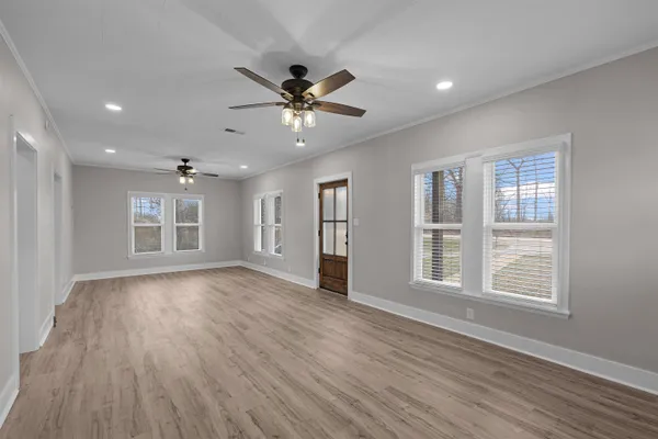 a view of an empty room with a window and wooden floor