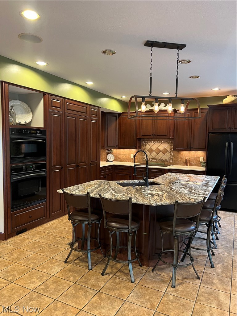 1457 Terrace Road Northwest New Philadelphia, OH 44663 - Photo 7 of 33 Kitchen with backsplash, light stone countertops, refrigerator, an island with sink, and light tile floors