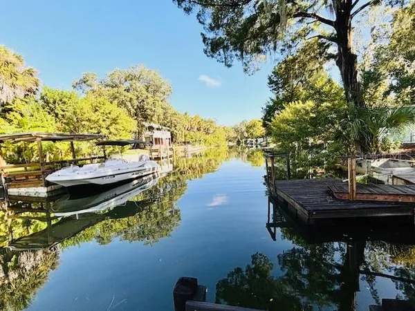 a view of a lake with lawn chairs under an umbrella