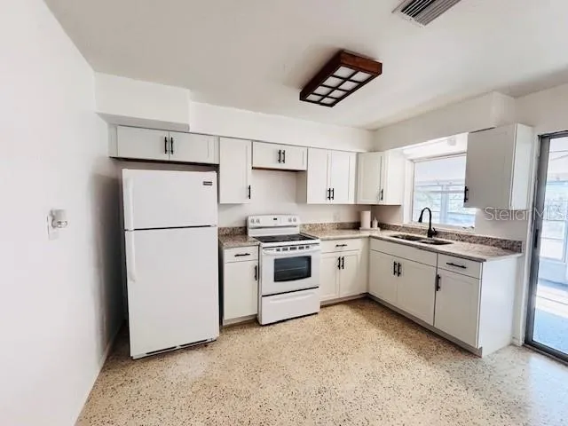 a kitchen with granite countertop white cabinets and white appliances