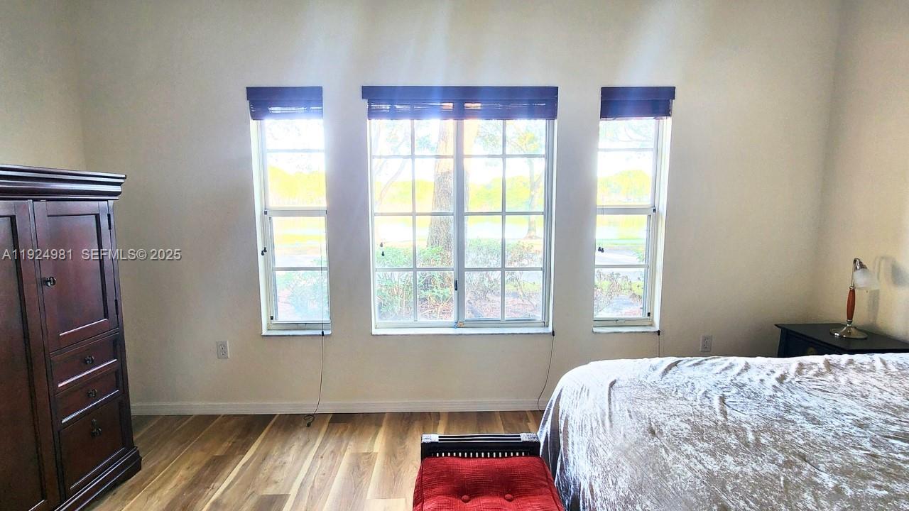 2557 Centergate Drive, Unit 101 Miramar, FL 33025 - Photo 11 of 14 a bedroom with a bed and wooden floor