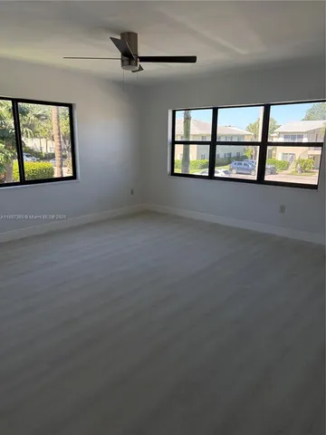 an empty room with windows and ceiling fan