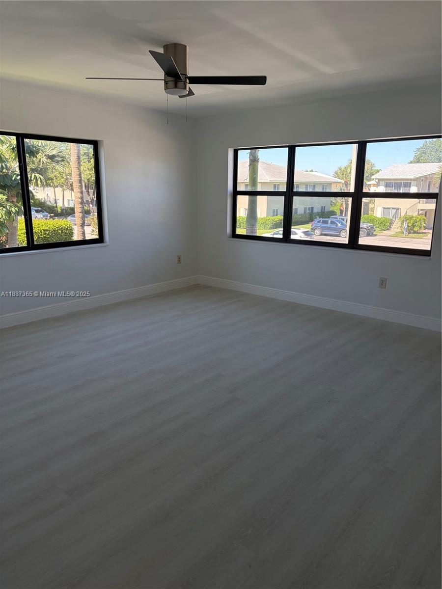 220 Southwest 7th Street, Unit 8 Boca Raton, FL 33432 - Photo 2 of 14 an empty room with windows and ceiling fan