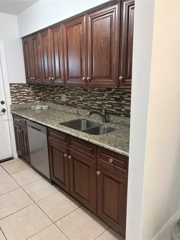 a view of kitchen with granite countertop wooden cabinets
