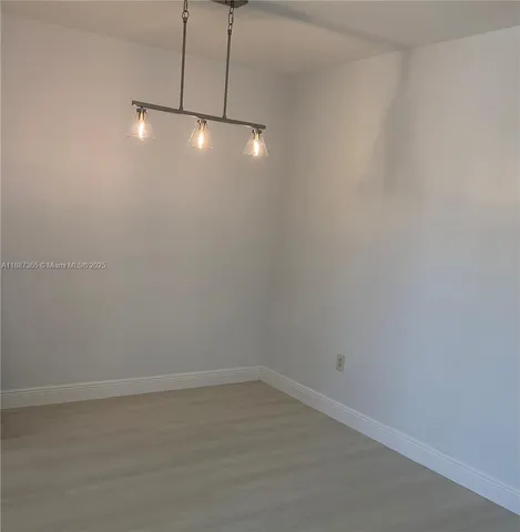 a view of an empty room with chandelier fan