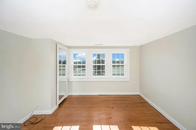 a view of a bedroom with wooden floor and windows