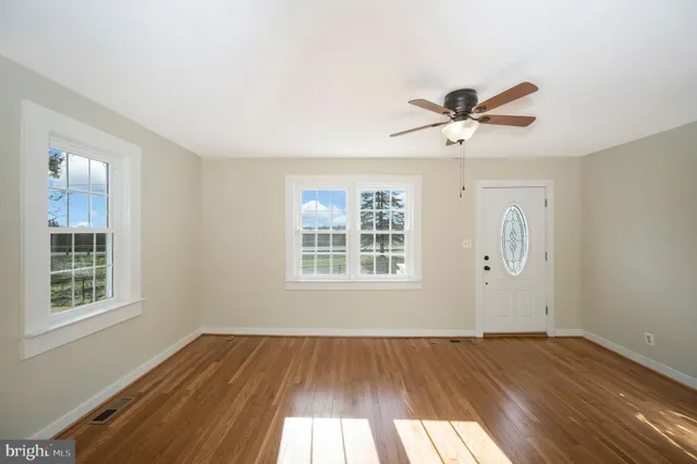 a view of an empty room with wooden floor and a window