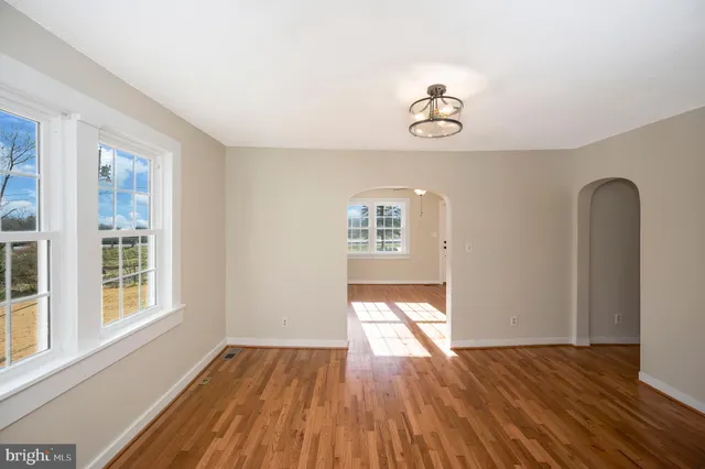 an empty room with windows and wooden floor