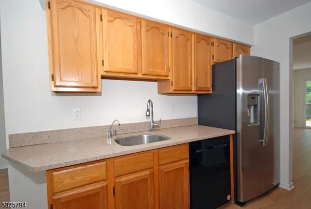 a kitchen with stainless steel appliances granite countertop a sink a refrigerator and cabinets