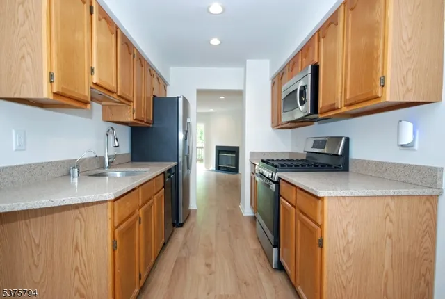 a kitchen with stainless steel appliances granite countertop a sink and dishwasher a stove top oven with wooden floor