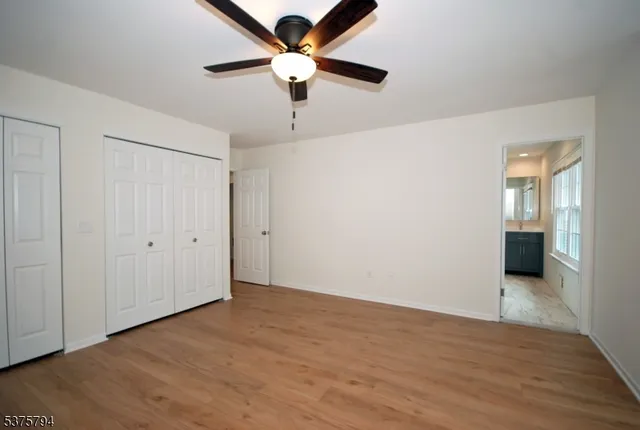 an empty room with wooden floor ceiling fan and windows