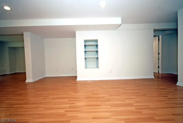 a view of an empty room with wooden floor and closet