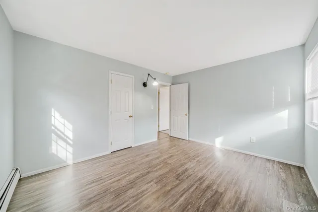 a view of an empty room with window and wooden floor