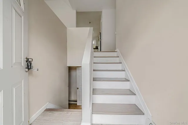 a view of staircase with white walls and white door