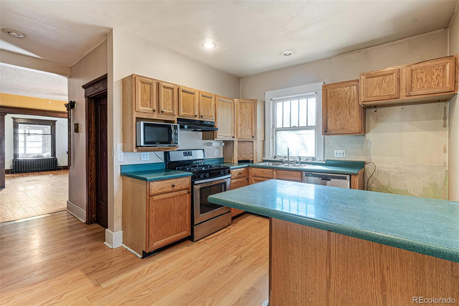 2089 South Logan Street Denver, CO 80210 - Photo 22 of 41 a kitchen with stainless steel appliances wooden floors a stove a microwave a sink and cabinets