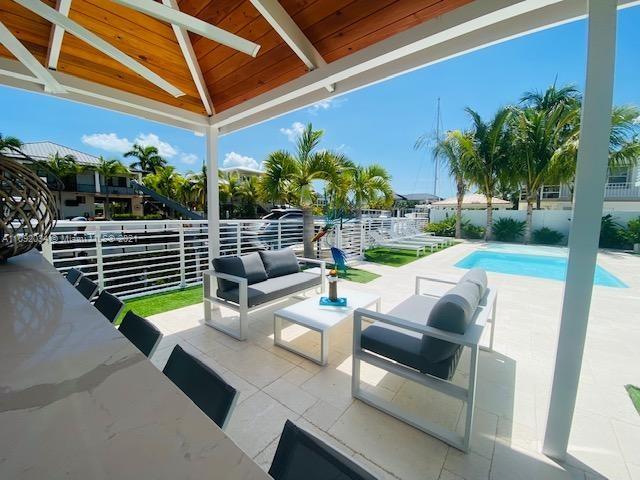 203 Atlantic Boulevard, Unit 203 Key Largo, FL 33037 - Photo 16 of 41 a view of a patio with couches chairs potted plants and palm trees