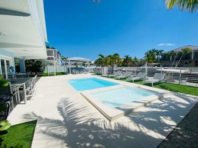 a view of a swimming pool with a patio and a yard