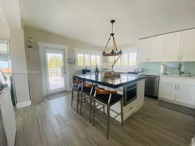 a kitchen with kitchen island granite countertop a sink cabinets and wooden floor