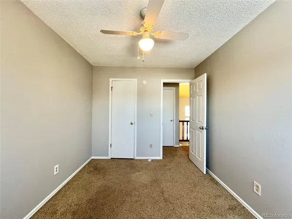 a view of an empty room and a ceiling fan and a window