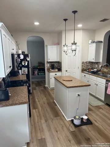 a kitchen with granite countertop a stove a sink dishwasher and a dining table with wooden floor