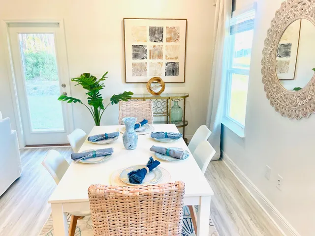 a kitchen with stainless steel appliances a dining table a refrigerator cabinets and wooden floor