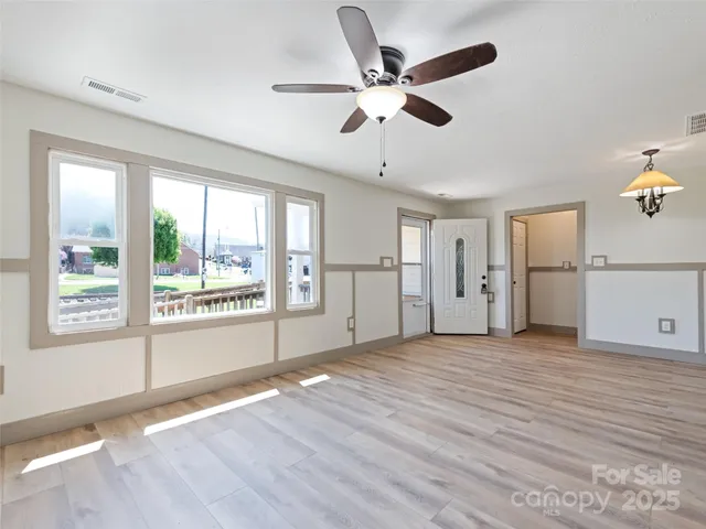 a view of an empty room with a window and wooden floor