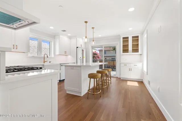a kitchen with a table chairs wooden floors and white stainless steel appliances