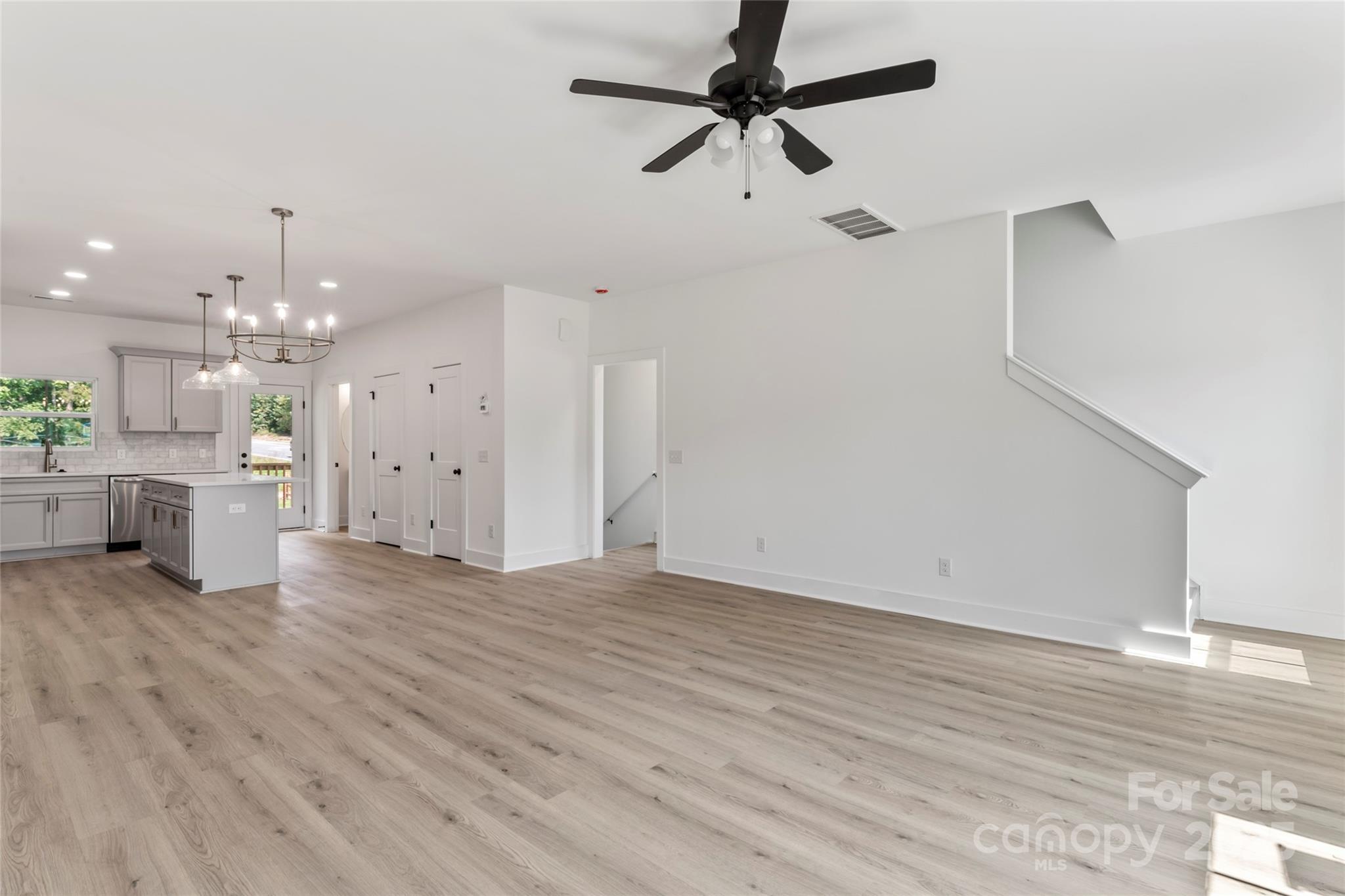 309 Yaupon Court, Unit 17 Fort Mill, SC 29708 - Photo 18 of 43 an empty room with wooden floor ceiling fan and kitchen view