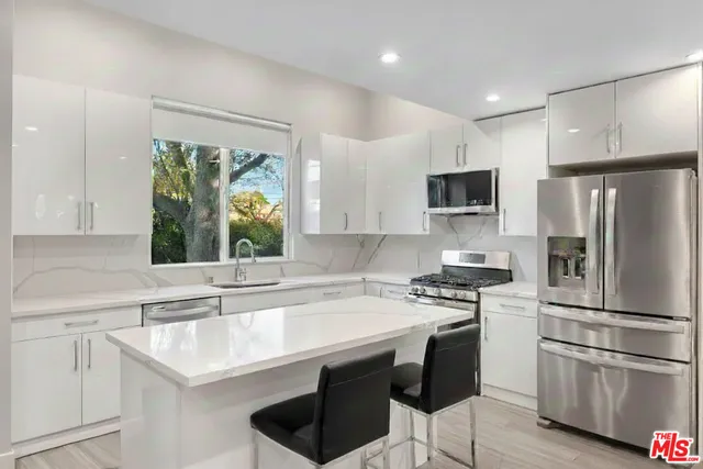 a kitchen with a sink a center island stainless steel appliances and cabinets
