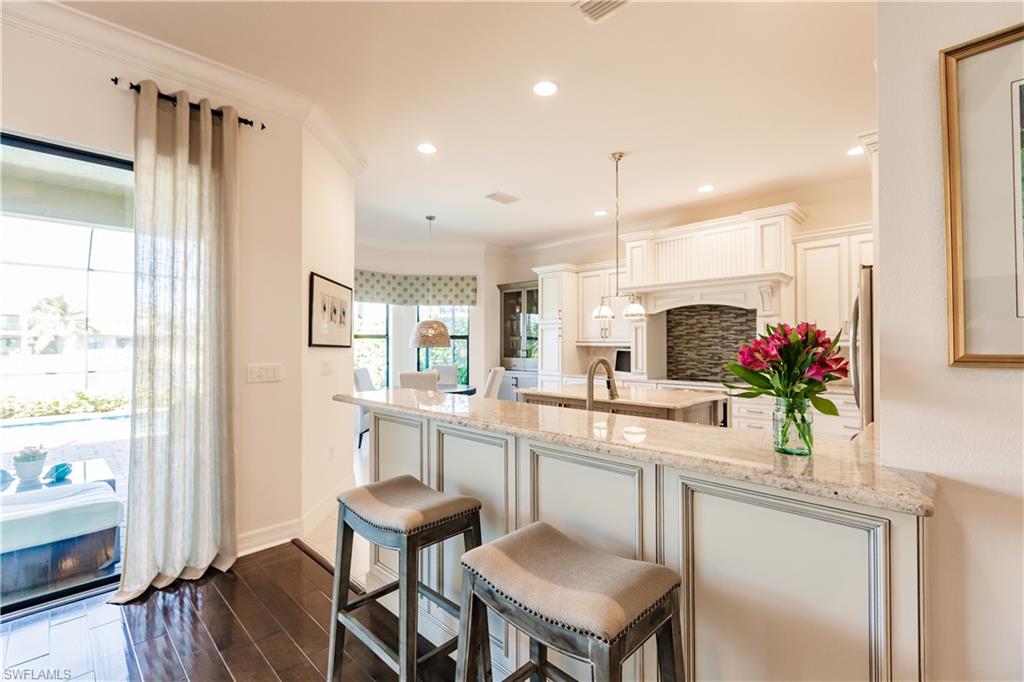 3432 Atlantic Circle Naples, FL 34119 - Photo 11 of 31 a kitchen with white cabinets and wooden floor