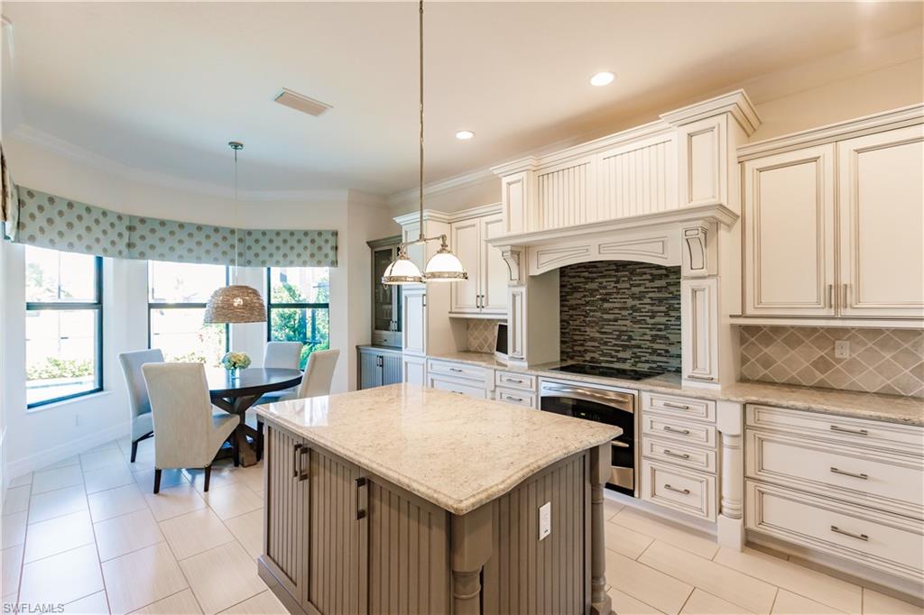 3432 Atlantic Circle Naples, FL 34119 - Photo 12 of 31 a open kitchen with granite countertop a stove a sink a dining table and chairs with wooden floor