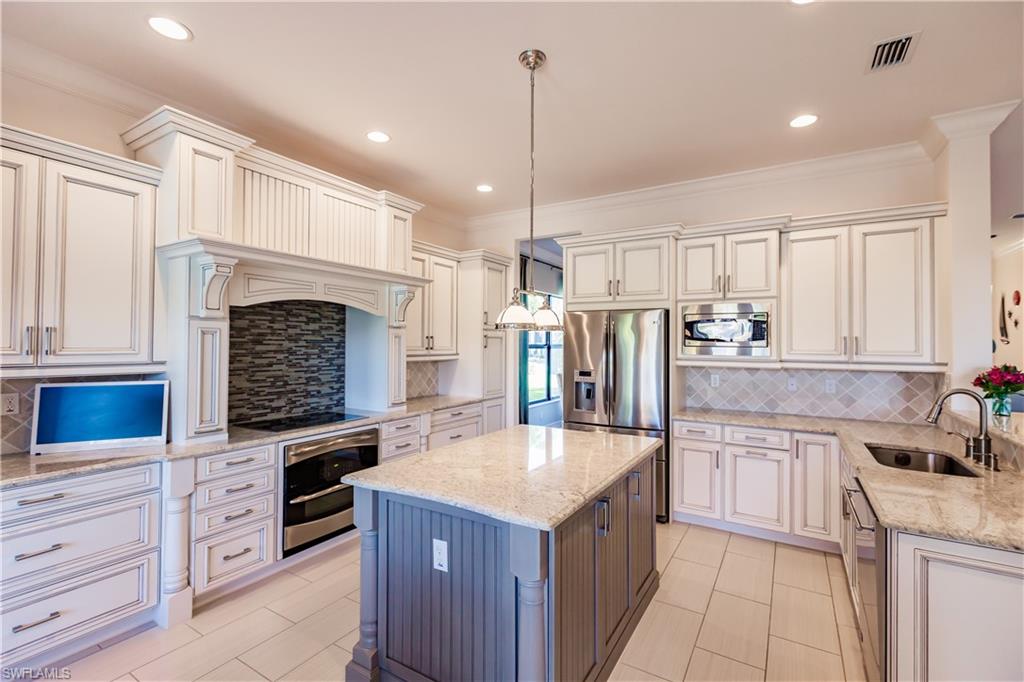 3432 Atlantic Circle Naples, FL 34119 - Photo 14 of 31 a kitchen with kitchen island a sink stove and refrigerator