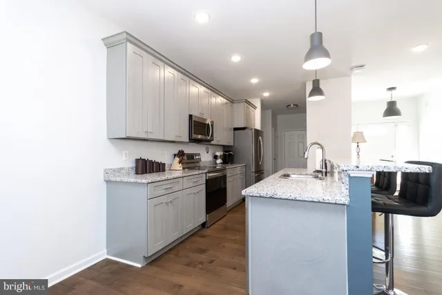 a kitchen with kitchen island granite countertop a sink appliances cabinets and furniture