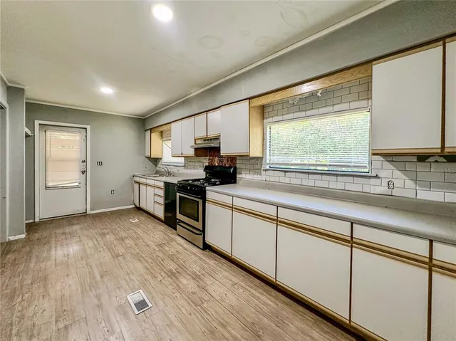an empty room with wooden floor fan and windows