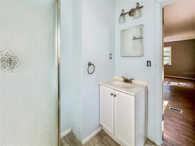 an empty room with chandelier fan and windows