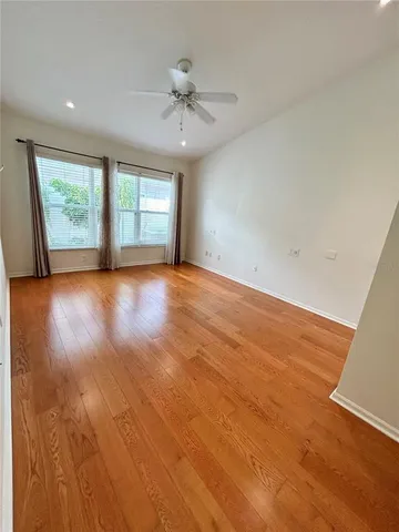 an empty room with wooden floor chandelier and windows