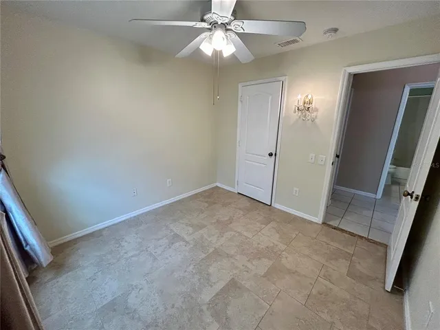 an empty room with chandelier fan and glass door