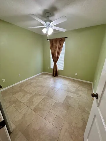 an empty room with chandelier fan and windows