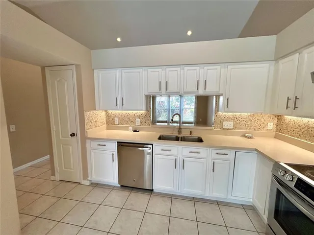 a kitchen with white cabinets appliances and sink