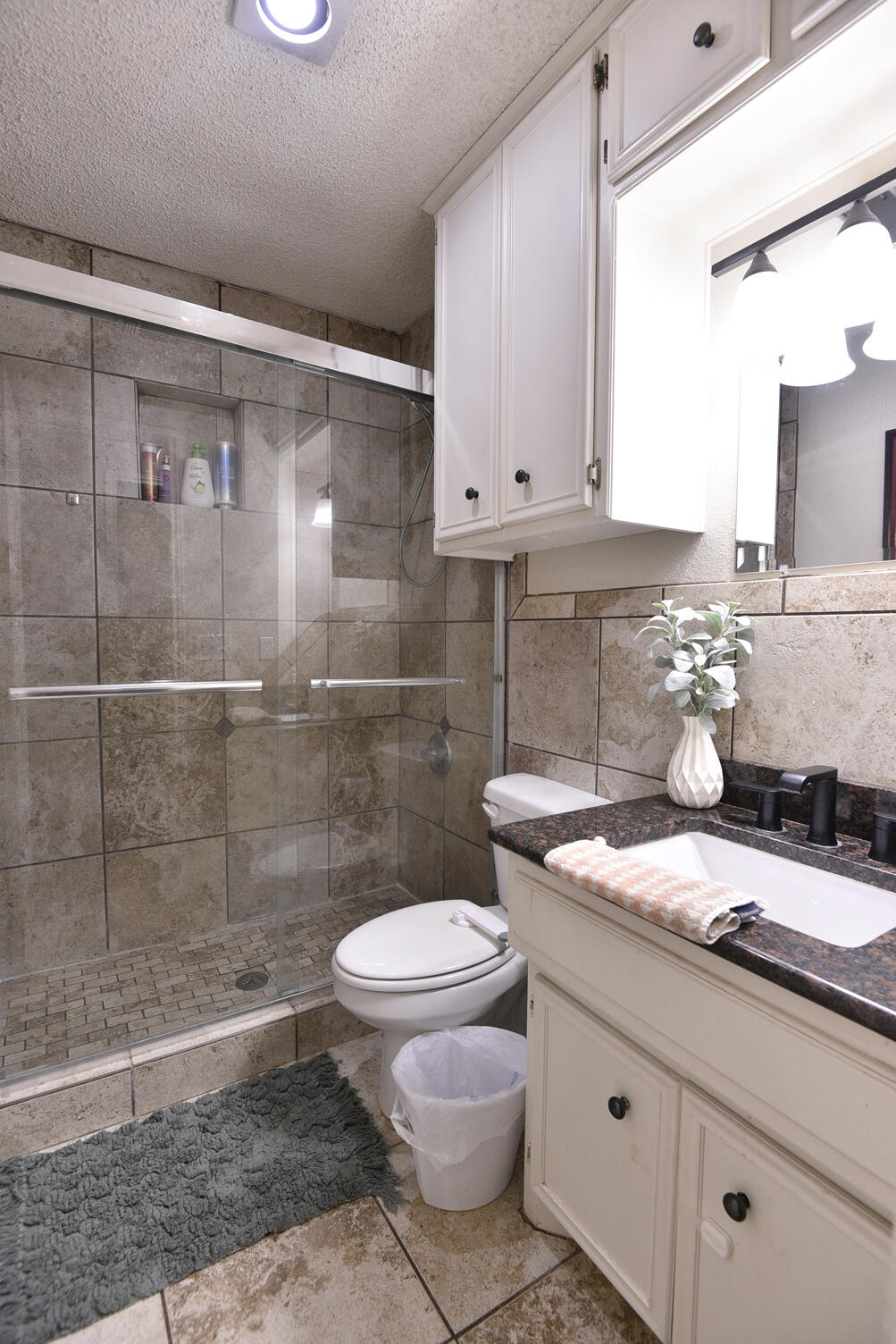 5202 93rd Street Lubbock, TX 79424 - Photo 23 of 28 a bathroom with a granite countertop sink a toilet and a shower