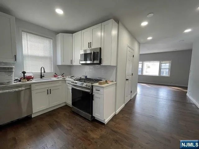 a kitchen with stainless steel appliances a white stove top oven sink and cabinets