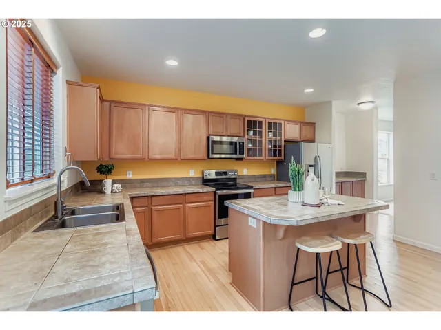 a open kitchen with stainless steel appliances granite countertop a stove top oven a sink dishwasher and cabinets with wooden floor