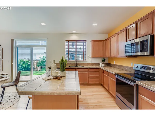 a kitchen with kitchen island granite countertop a stove top oven a sink dishwasher a dining table and chairs with wooden floor