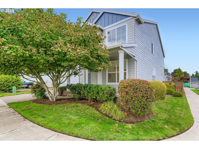 a view of a white house next to a yard with big trees
