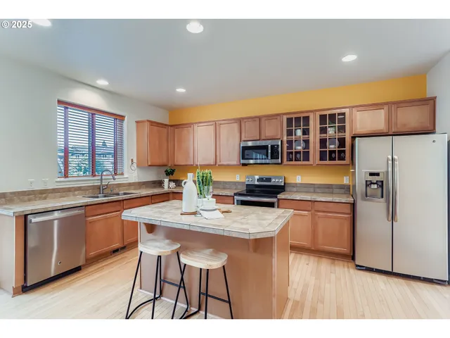 a kitchen with stainless steel appliances granite countertop a refrigerator a sink dishwasher a stove with wooden cabinets and floor