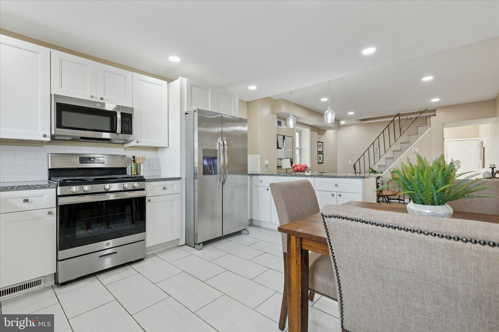 39 West Front Street Bridgeport, PA 19405 - Photo 13 of 23 a kitchen with stainless steel appliances kitchen island granite countertop a refrigerator a stove a microwave oven a sink with a dining table and chairs