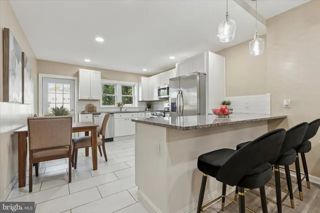a kitchen with granite countertop white cabinets dining table and chairs