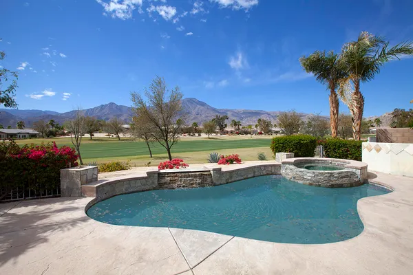 a view of a swimming pool and lounge chairs in the patio