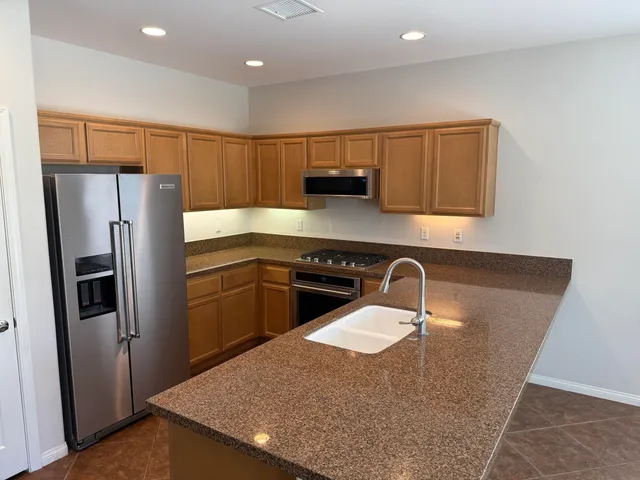 a kitchen with stainless steel appliances granite countertop a refrigerator a sink a stove a microwave a counter top and oven