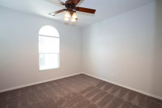 an empty room with windows and chandelier fan